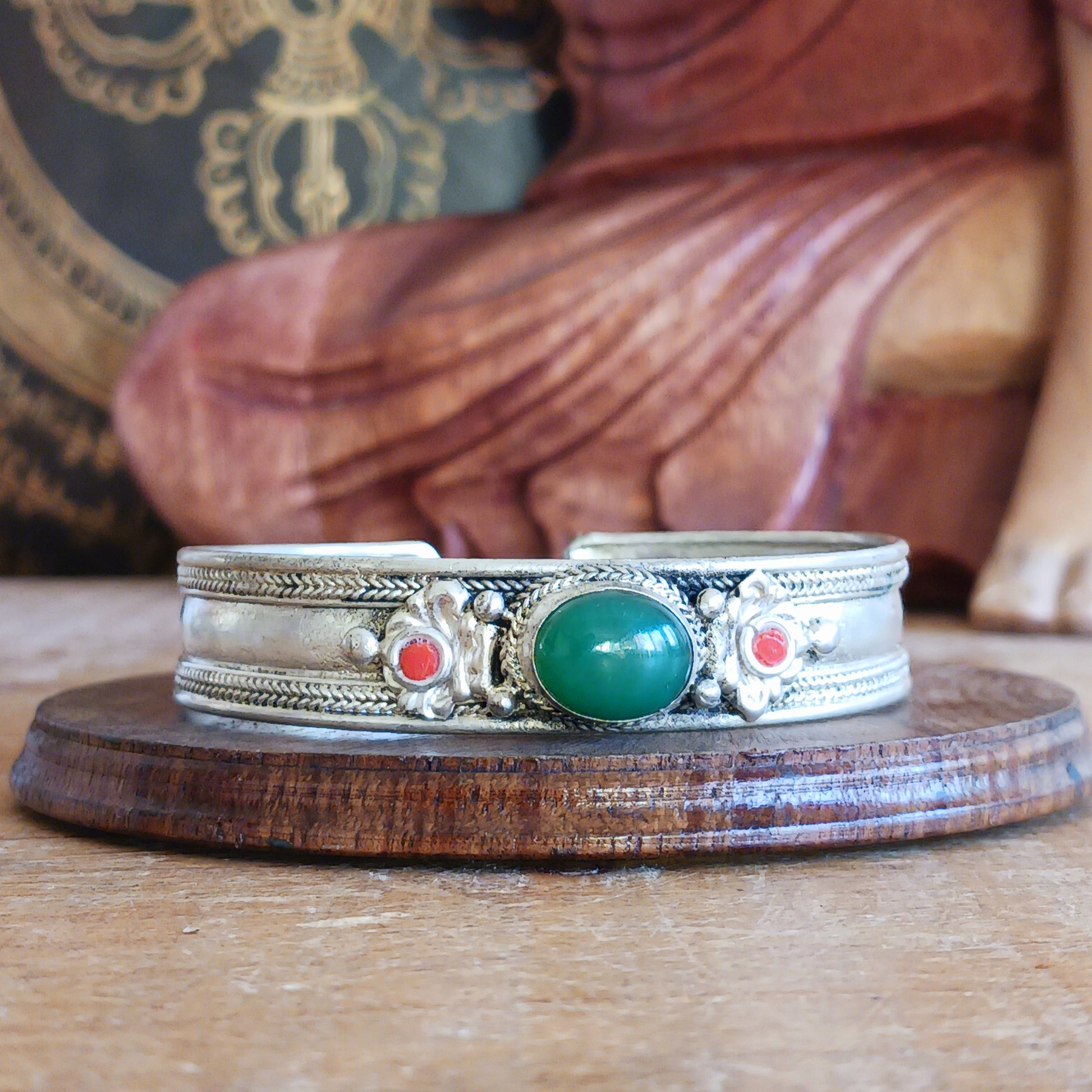 Add a touch of elegance and meaning to your jewellery collection with this handcrafted Nepalese bangle. Made from high-quality white metal, each bangle features a single green aventurine stone, symbolizing luck and harmony, flanked by two vibrant red drop beads for a striking contrast.