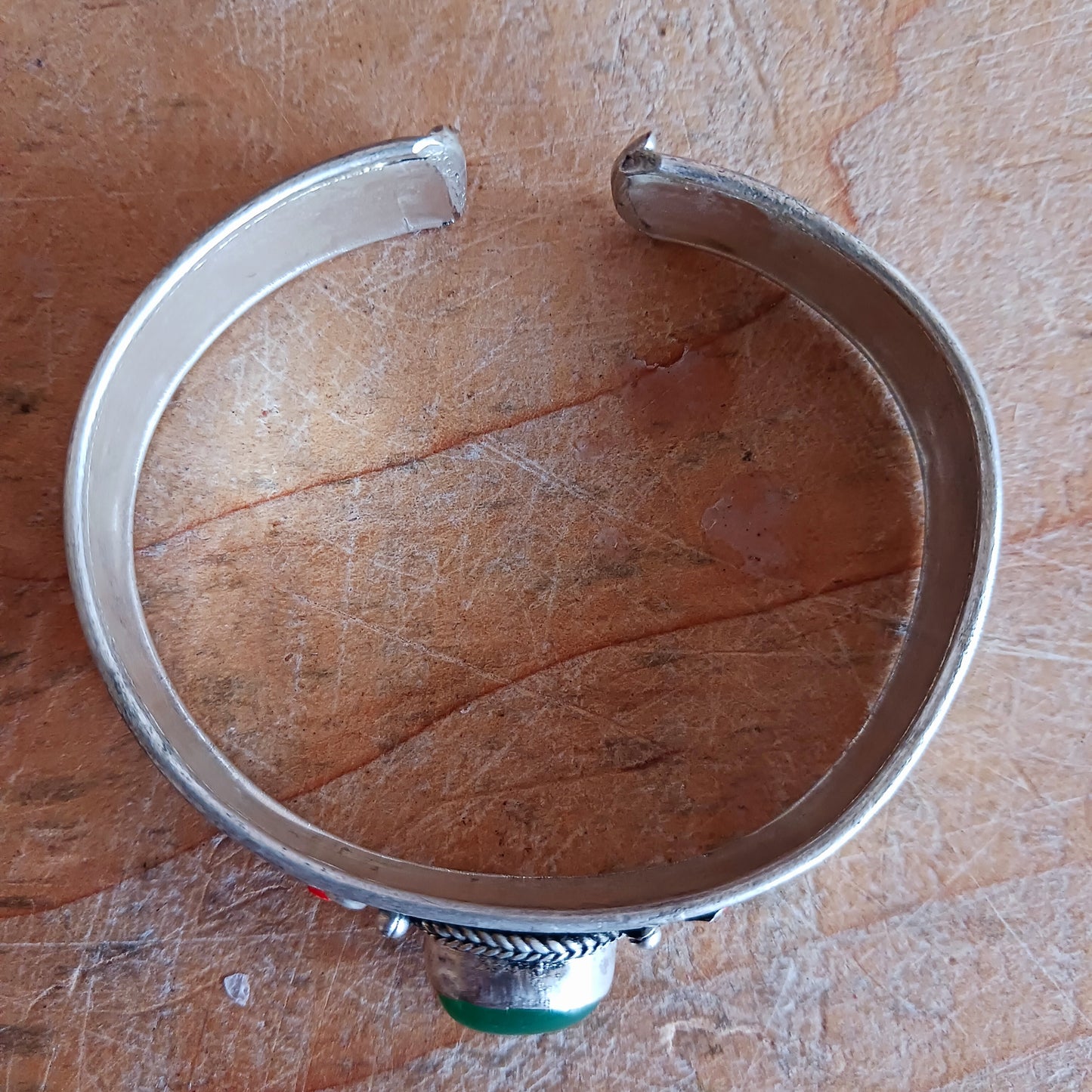 Add a touch of elegance and meaning to your jewellery collection with this handcrafted Nepalese bangle. Made from high-quality white metal, each bangle features a single green aventurine stone, symbolizing luck and harmony, flanked by two vibrant red drop beads for a striking contrast.