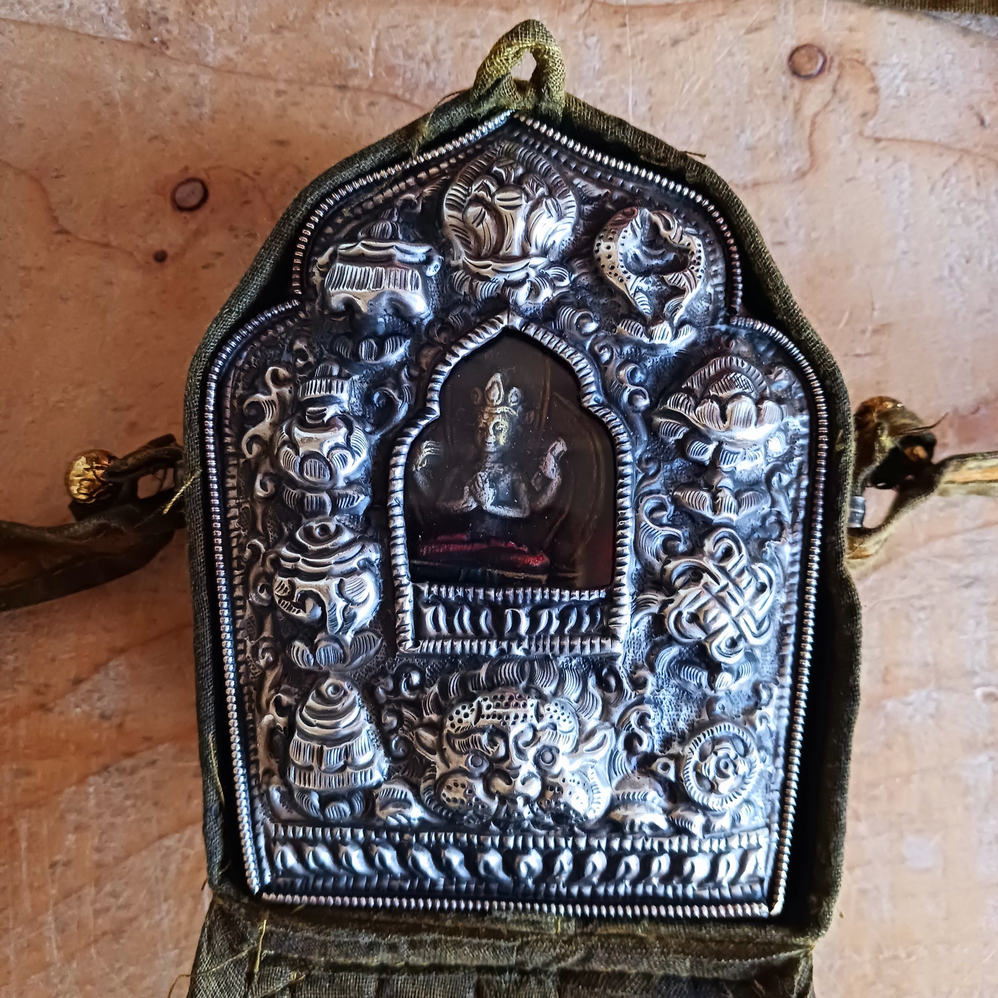 Discover the spiritual power of the Tibetan Ghau, a portable shrine and traditional prayer box used to carry sacred relics, charms, and medicinal herbs. Crafted by skilled Tibetan refugee artisans in Nepal, each Ghau serves as a portable shrine offering protection and blessings during travel. Wear it as a pendant around your neck or hang it from a waist sash or belt. This handcrafted piece is not only a spiritual talisman but also a beautiful work of art, connecting you to centuries-old Tibetan traditions.