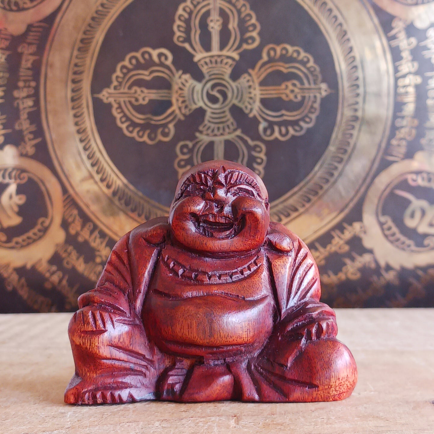 This mini hard carved wooden Laughing Buddha statue represents Budai, the beloved figure of joy, abundance, and contentment in Buddhist tradition. Carved in wood and full of character, Budai is traditionally depicted as a bald monk with a joyful smile, wearing simple robes and holding prayer beads.