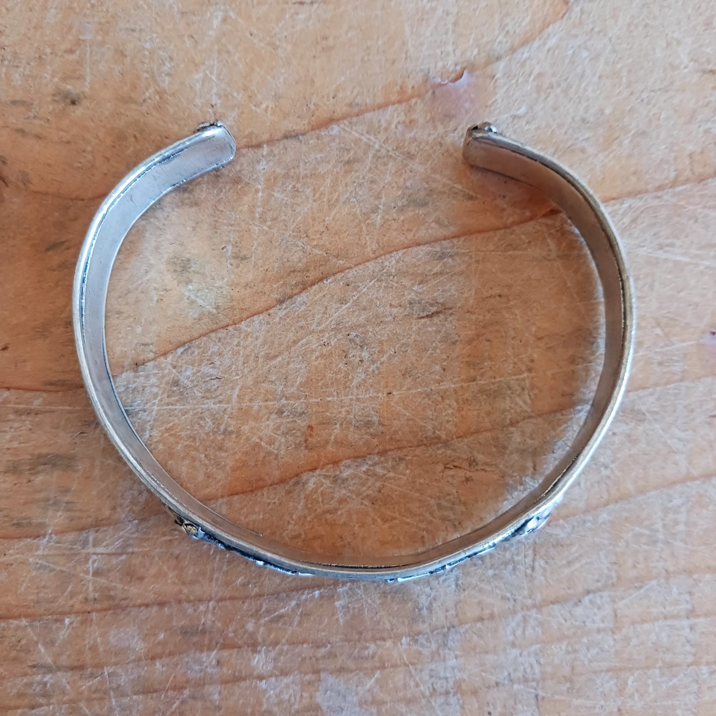 This Tibetan adjustable mantra bangle is a timeless piece of spiritual jewellery, handcrafted by skilled artisans in Nepal. Made from traditional Tibetan White Metal, the bangle features two small coral stones and engraved script inspired by ancient Tibetan culture and symbolism.