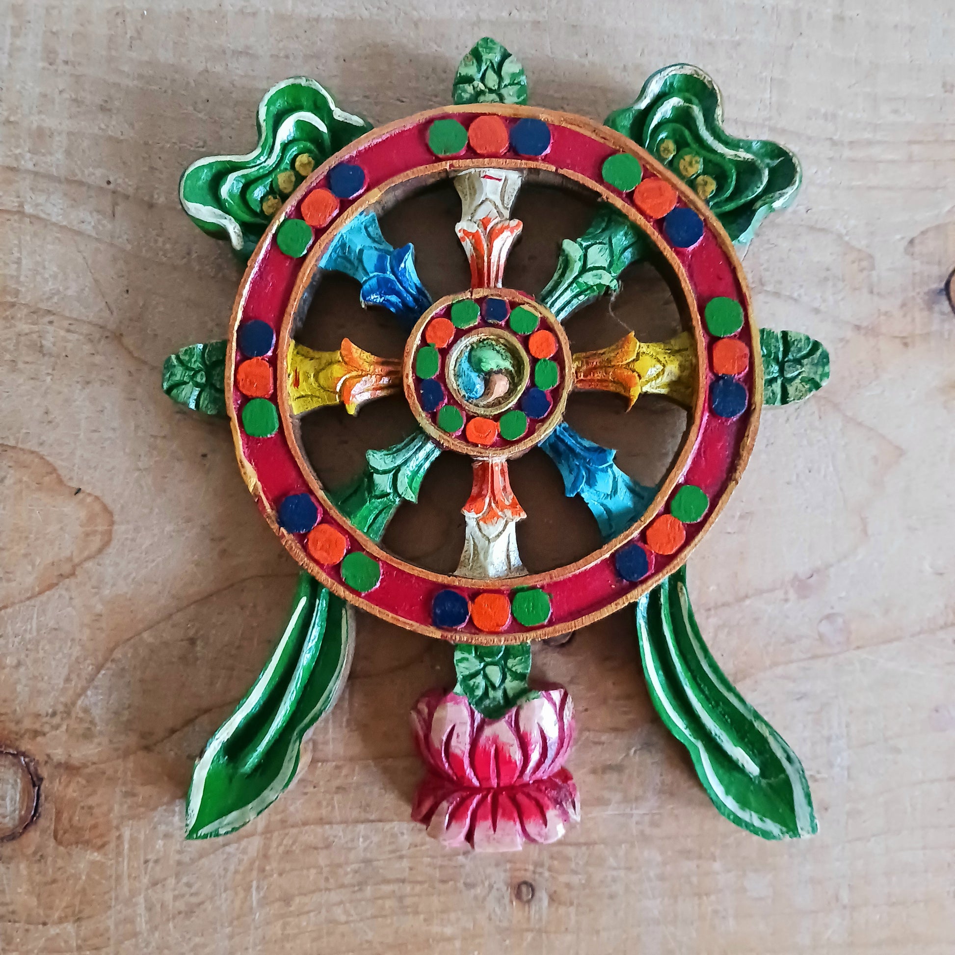 This colourful and unique hand painted dharma wheel wall hanging has been hand caved from one piece of wood.