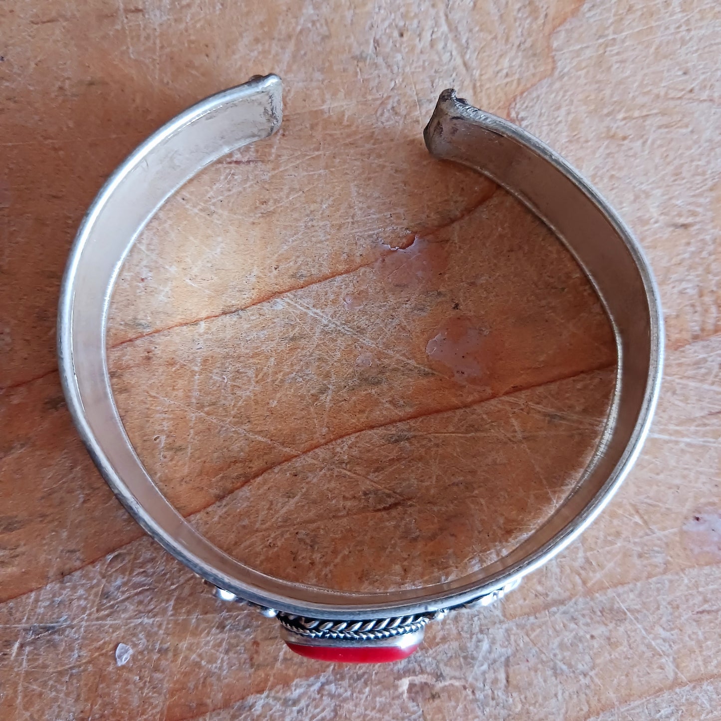 Add a touch of elegance and meaning to your jewellery collection with this handcrafted Nepalese bangle. Made from high-quality white metal, the bangle features a single coral stone.