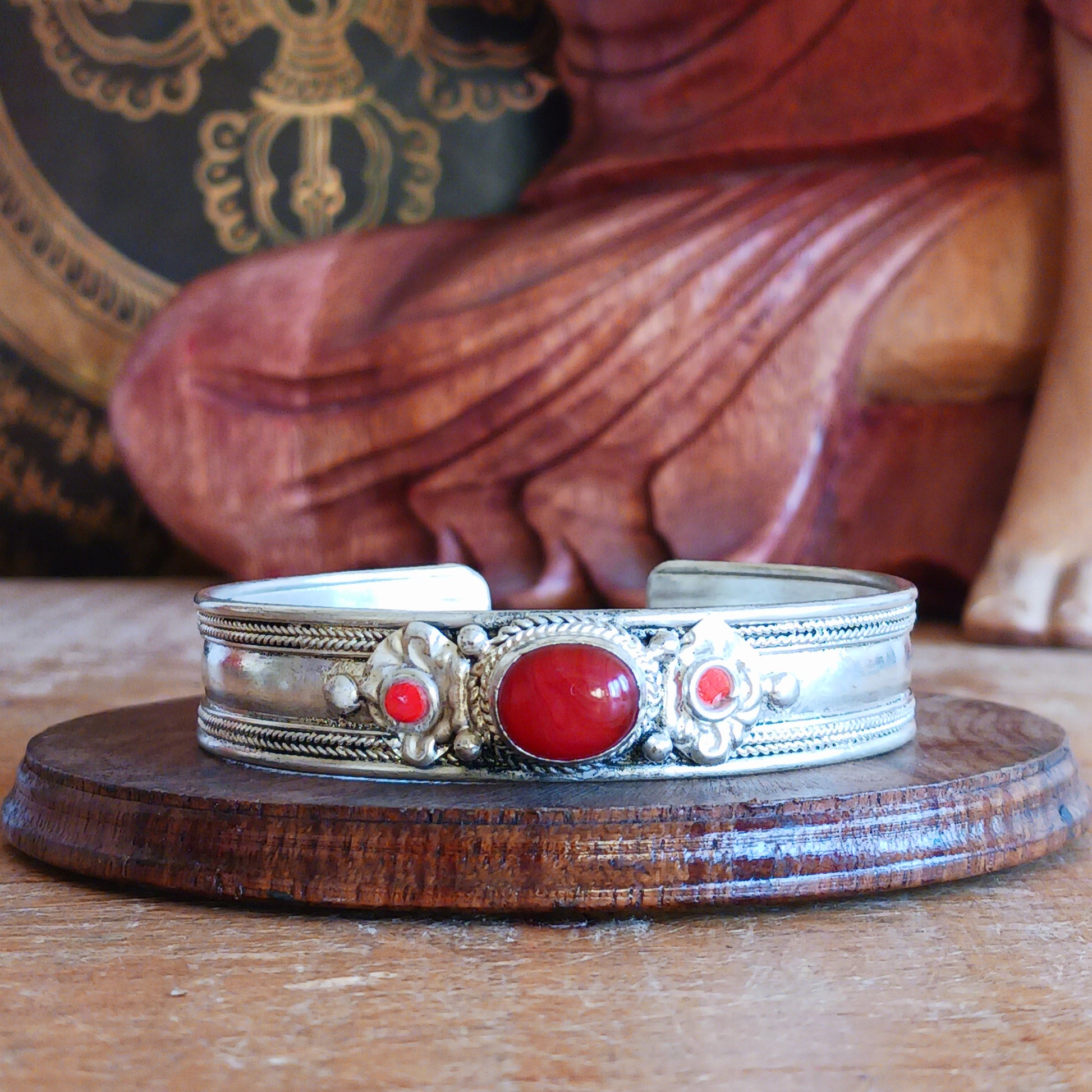 Add a touch of elegance and meaning to your jewellery collection with this handcrafted Nepalese bangle. Made from high-quality white metal, each bangle features a single coral stone, symbolizing luck and harmony, flanked by two vibrant red drop beads for a striking contrast.