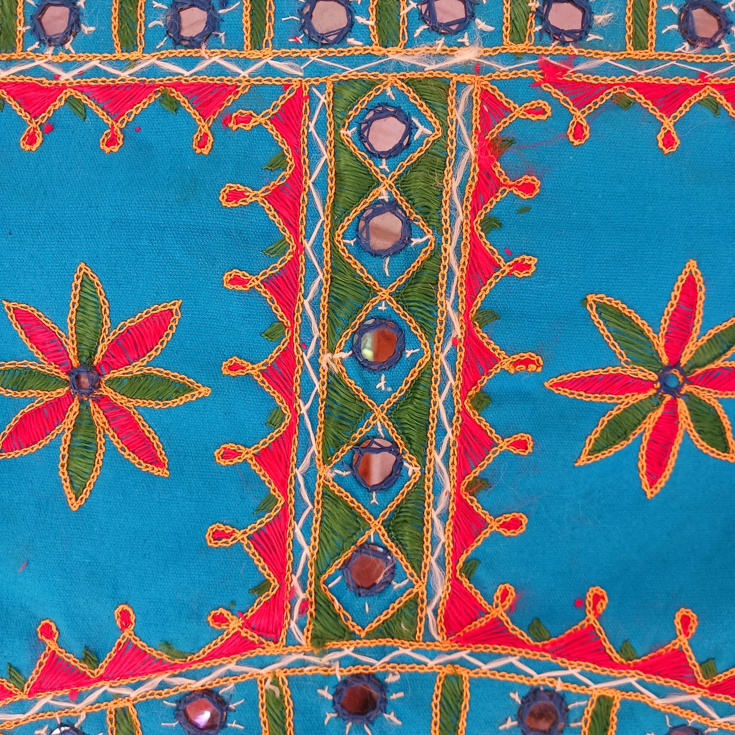 This beautiful turquoise Indian arch toran features two orange elephants with flowers either side and is adorned with mirrors and finished with tassels. This lovely toran has been meticulously hand-sewn and beautifully finished.  It really is a unique work of art.