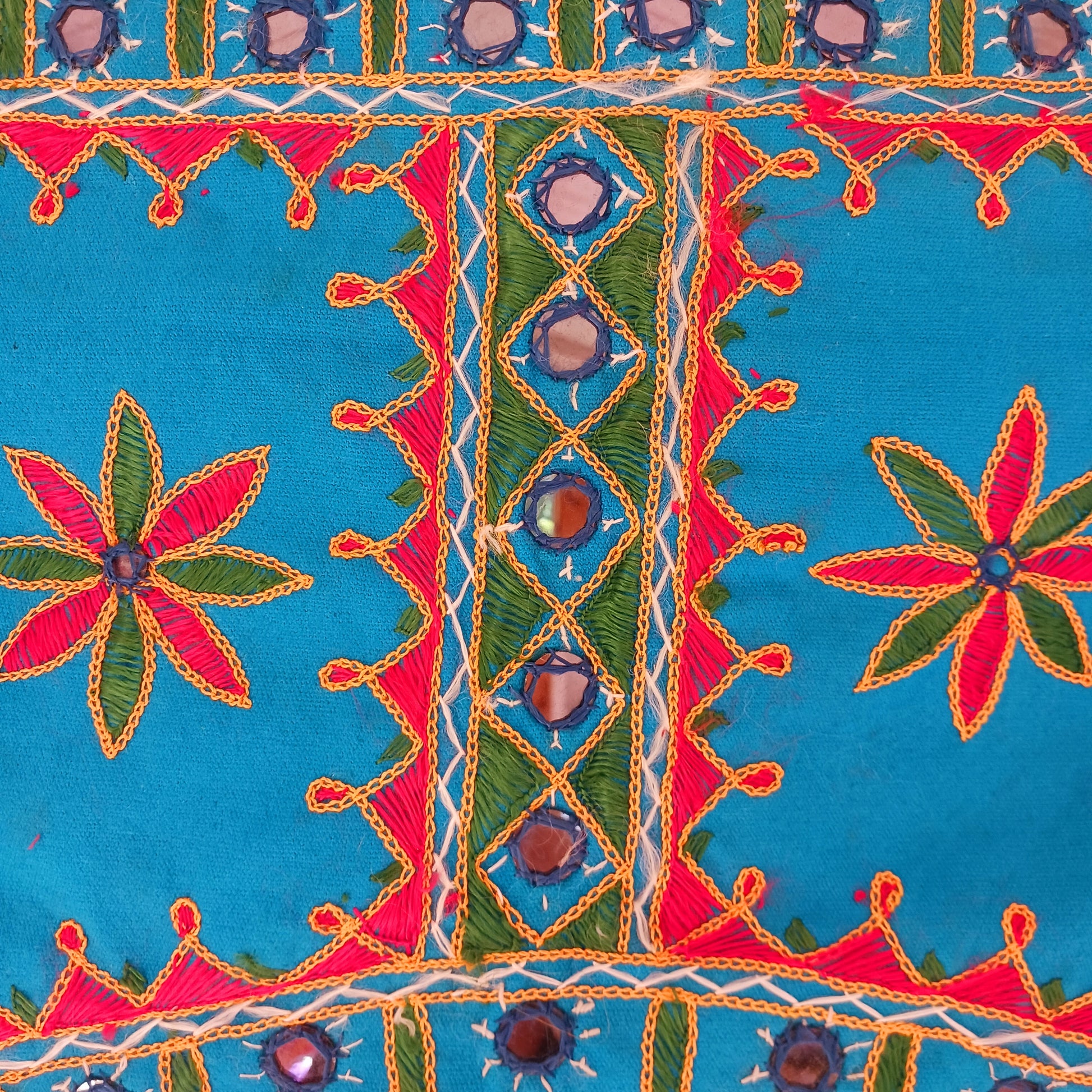 This beautiful turquoise Indian arch toran features two orange elephants with flowers either side and is adorned with mirrors and finished with tassels. This lovely toran has been meticulously hand-sewn and beautifully finished.  It really is a unique work of art.