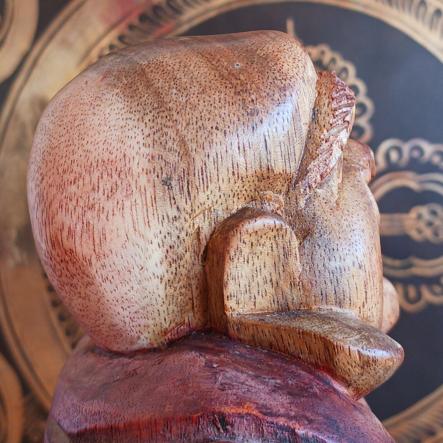 This charming Hand Carved Laughing Buddha is seated in a relaxed pose with a broad, joyful grin and rounded belly, beautifully carved from warm two-tone wood. The natural wood grain is enhanced with a protective varnish, highlighting the intricate details of his robes, prayer beads and expressive face.