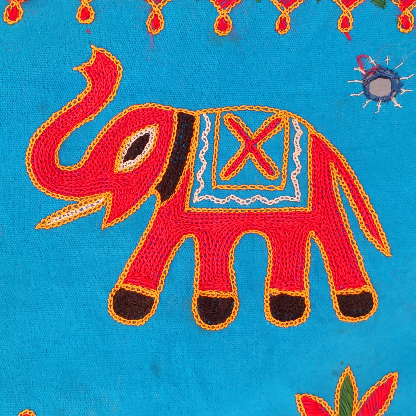This beautiful turquoise Indian arch toran features two orange elephants with flowers either side and is adorned with mirrors and finished with tassels. This lovely toran has been meticulously hand-sewn and beautifully finished.  It really is a unique work of art.