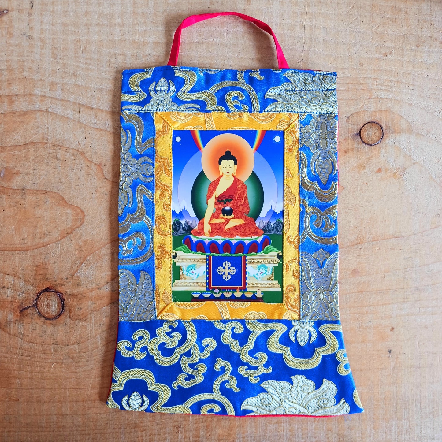 Beautiful small thangka of Shakyamuni Buddha with brocade border. A perfect spiritual art piece for meditation or home altar decoration.