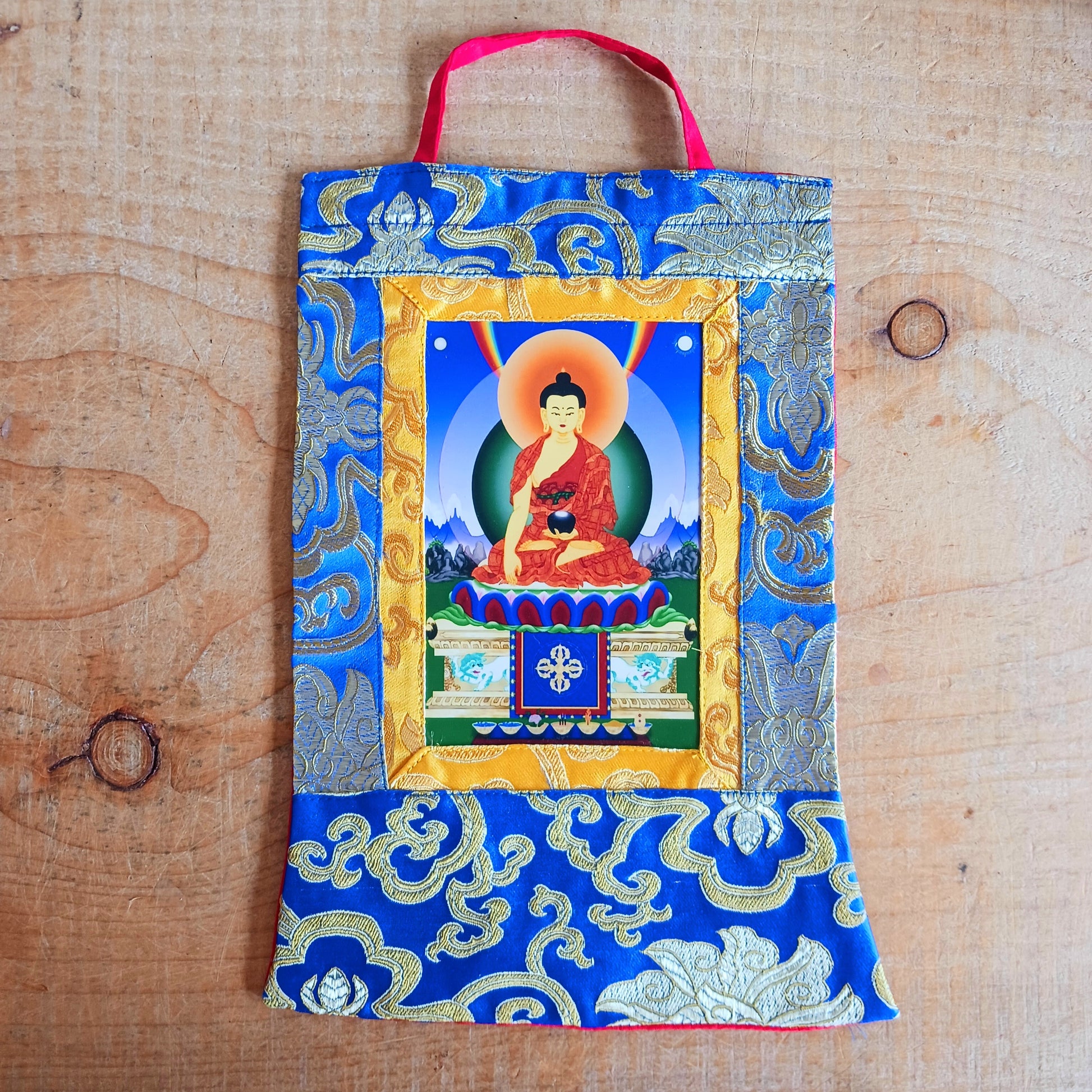 Beautiful small thangka of Shakyamuni Buddha with brocade border. A perfect spiritual art piece for meditation or home altar decoration.