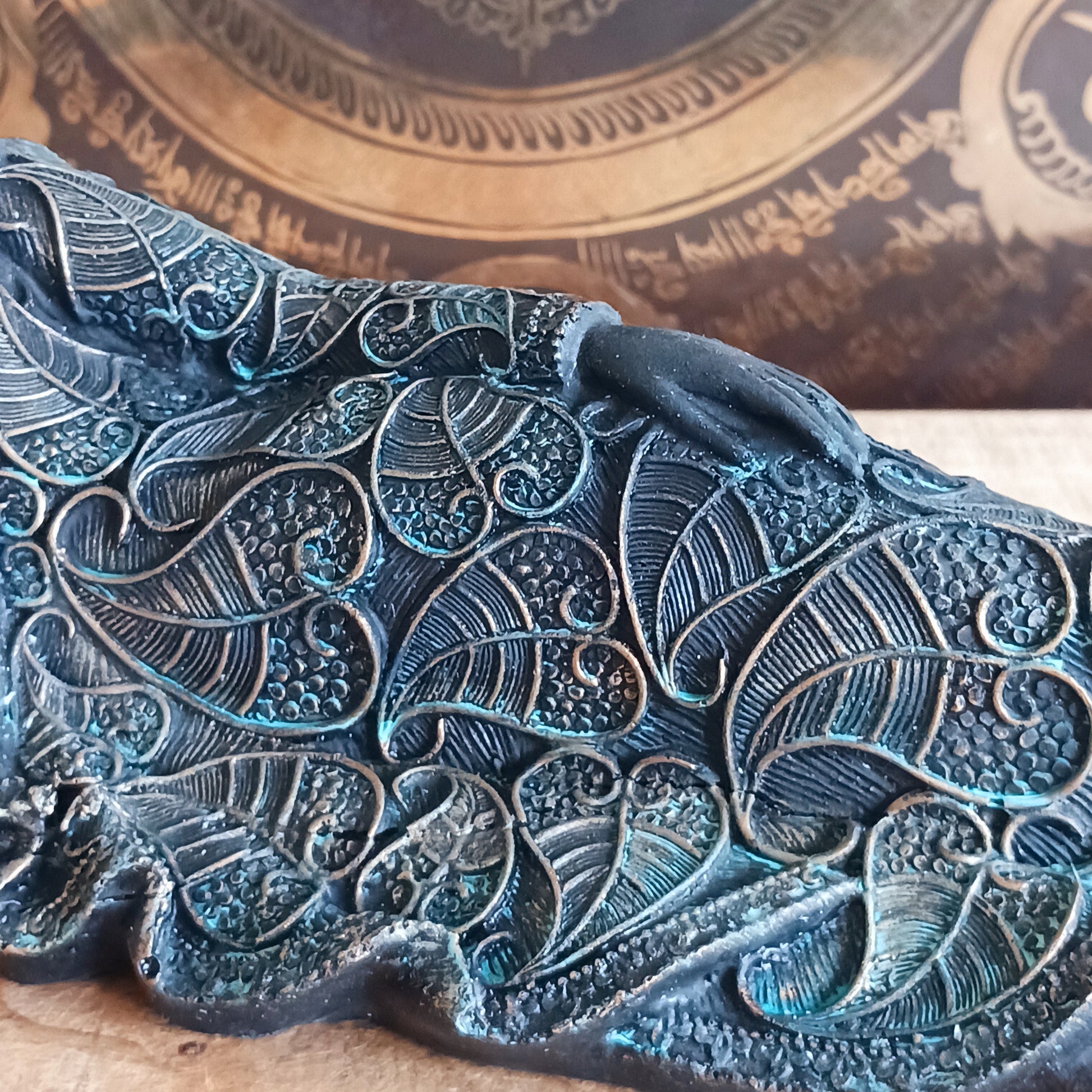 The statue features the Buddha in a graceful reclining pose, symbolizing his entry into nirvana. His left arm rests peacefully by his side, while his right hand cradles his head in a gesture of repose. The robe is intricately adorned with bodhi leaf motifs—sacred symbols of enlightenment and spiritual awakening.