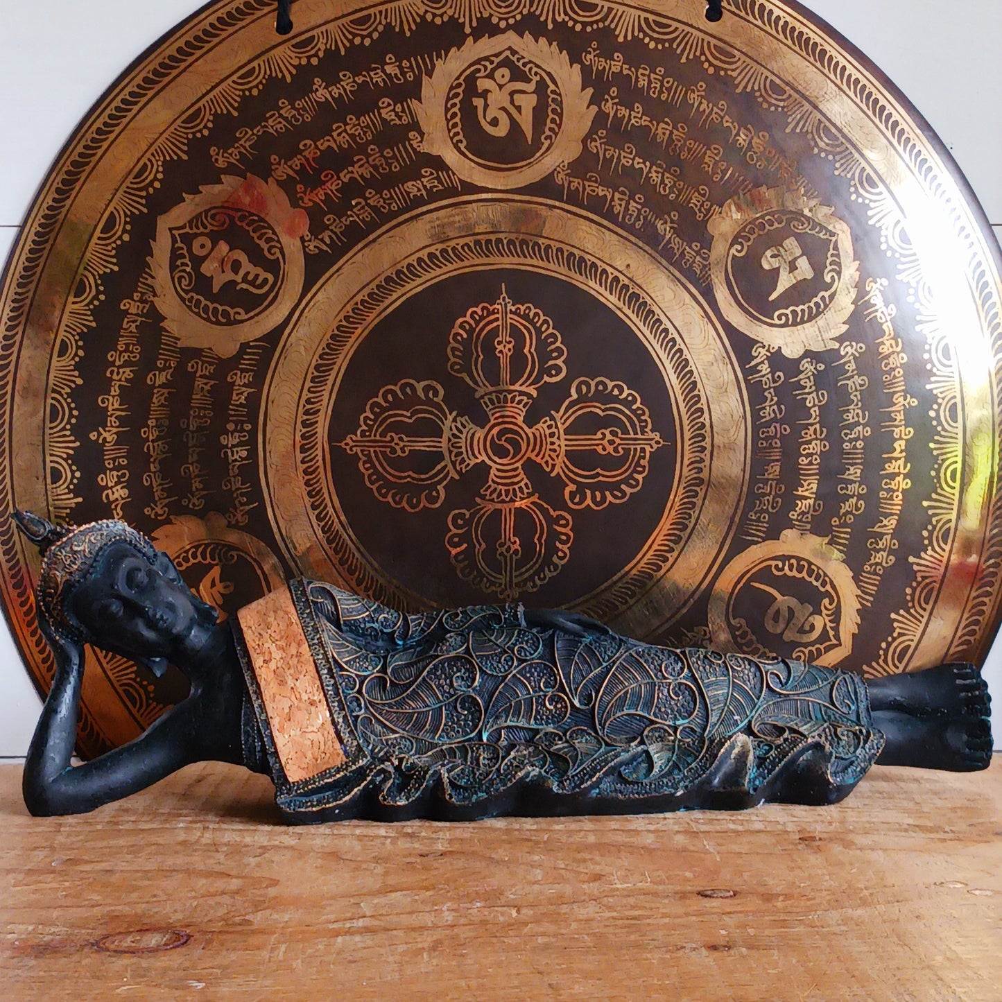 The statue features the Buddha in a graceful reclining pose, symbolizing his entry into nirvana. His left arm rests peacefully by his side, while his right hand cradles his head in a gesture of repose. The robe is intricately adorned with bodhi leaf motifs—sacred symbols of enlightenment and spiritual awakening.