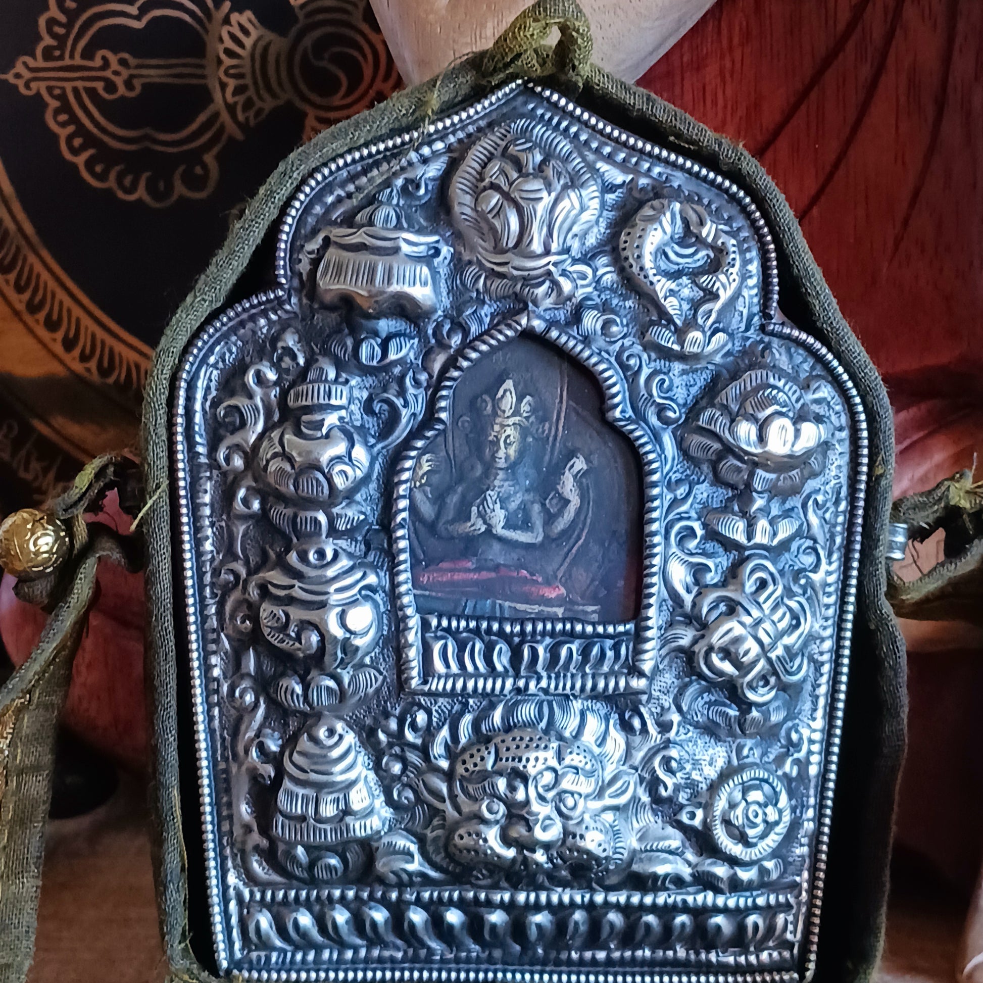 Discover the spiritual power of the Tibetan Ghau, a portable shrine and traditional prayer box used to carry sacred relics, charms, and medicinal herbs. Crafted by skilled Tibetan refugee artisans in Nepal, each Ghau serves as a portable shrine offering protection and blessings during travel. Wear it as a pendant around your neck or hang it from a waist sash or belt. This handcrafted piece is not only a spiritual talisman but also a beautiful work of art, connecting you to centuries-old Tibetan traditions.