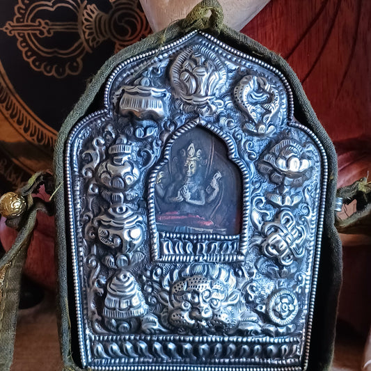 Discover the spiritual power of the Tibetan Ghau, a portable shrine and traditional prayer box used to carry sacred relics, charms, and medicinal herbs. Crafted by skilled Tibetan refugee artisans in Nepal, each Ghau serves as a portable shrine offering protection and blessings during travel. Wear it as a pendant around your neck or hang it from a waist sash or belt. This handcrafted piece is not only a spiritual talisman but also a beautiful work of art, connecting you to centuries-old Tibetan traditions.
