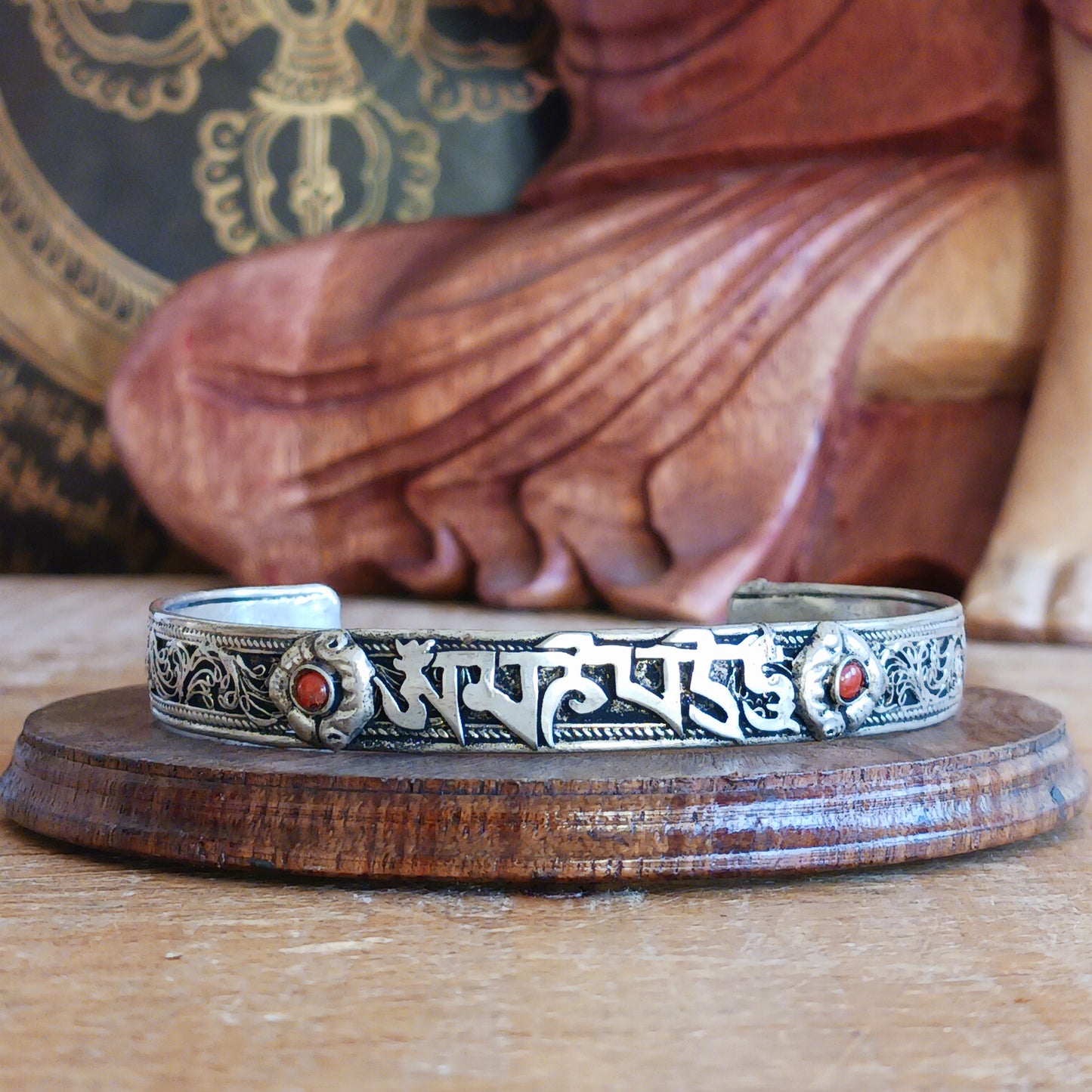 This Tibetan adjustable mantra bangle is a timeless piece of spiritual jewellery, handcrafted by skilled artisans in Nepal. Made from traditional Tibetan White Metal, the bangle features two small coral stones and engraved script inspired by ancient Tibetan culture and symbolism.