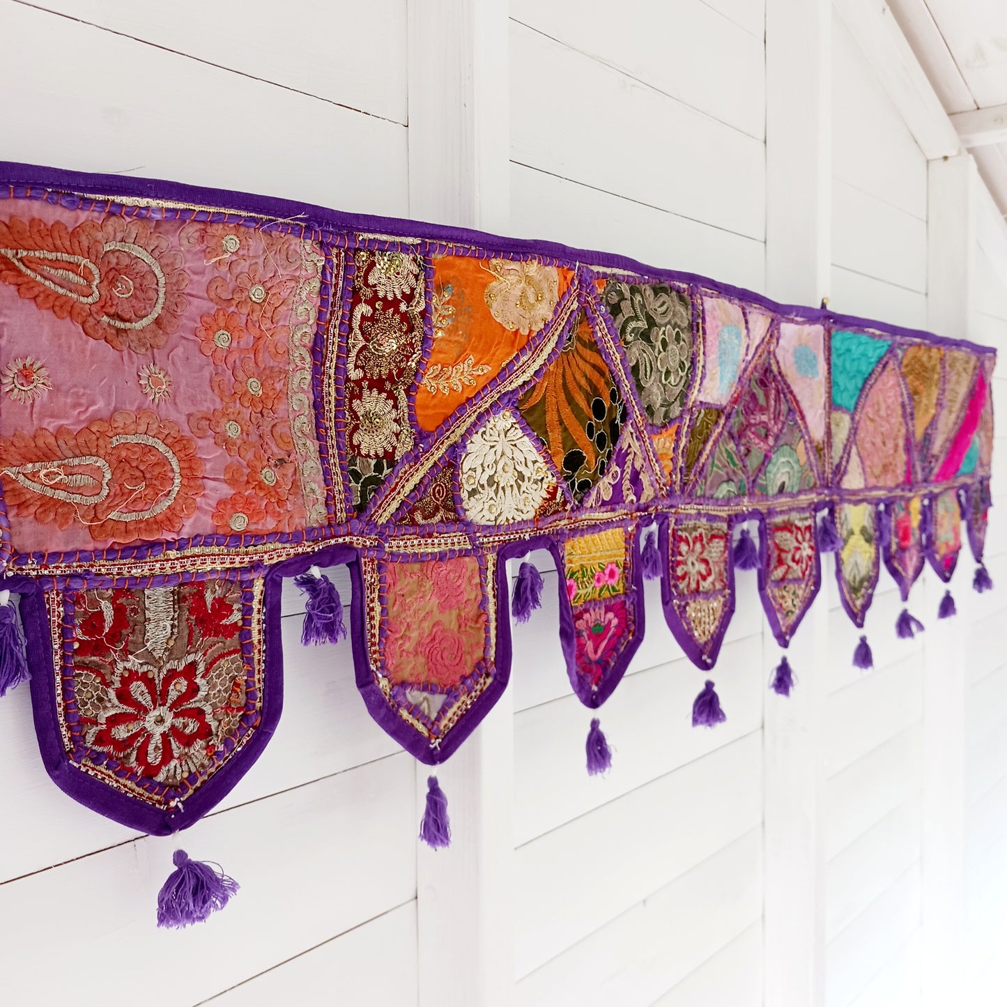 This long and beautifully intricate Indian Toran has been handmade from patches of vintage fabrics, wedding saris and recycled fabrics. It will be a unique addition to any home and bring vibrancy of colour and embellishment.