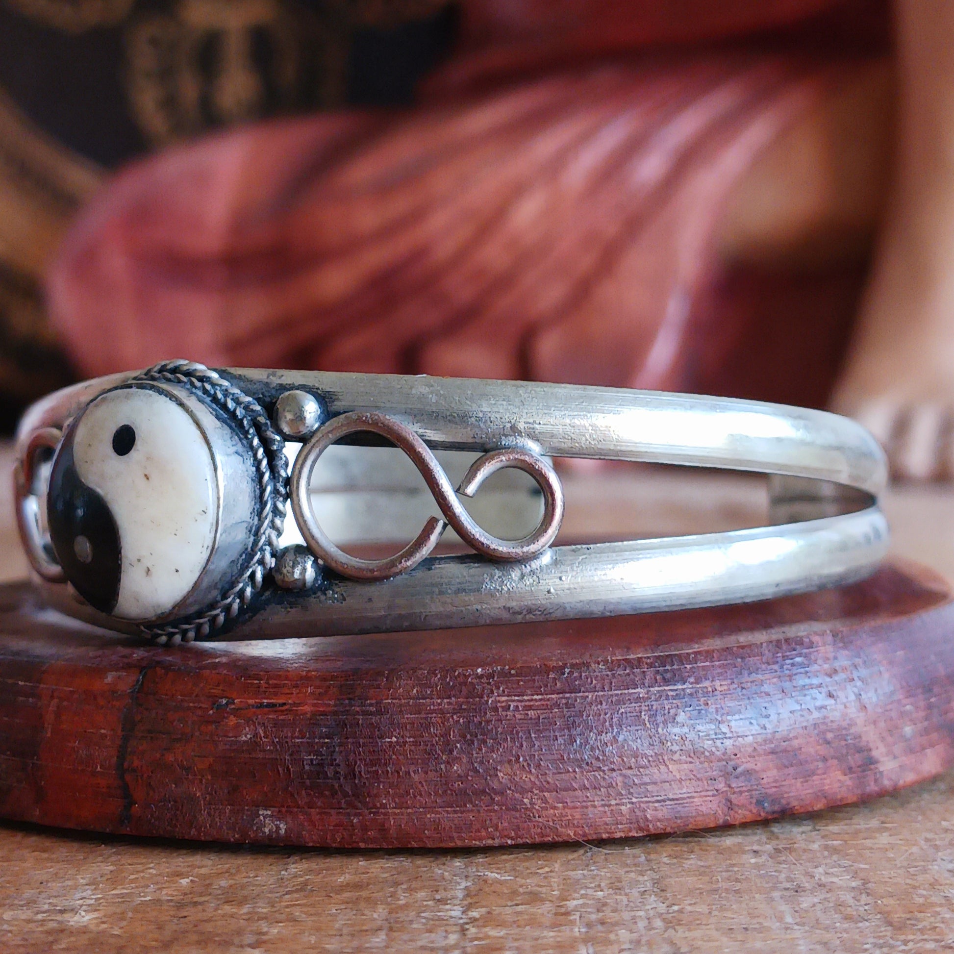 This white metal Yin Yang bracelet has been carefully hand crafted in local Nepalese workshops by skilled artisans. Each piece is individual its presented in a hand made traditional pouch. The pouches were designed to both utilize fabric left after garment production and to generate household employment for Nepali women. The production of these pouches began over 30 years ago and now 15-20 women are in continuous work within this project.