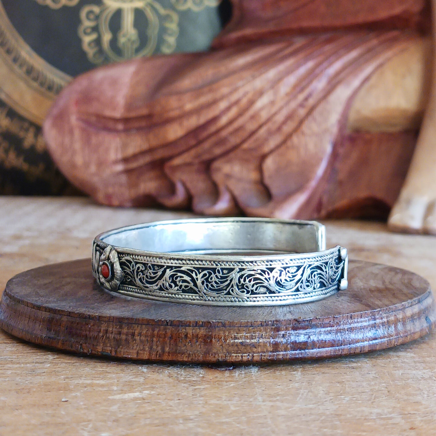 This Tibetan adjustable mantra bangle is a timeless piece of spiritual jewellery, handcrafted by skilled artisans in Nepal. Made from traditional Tibetan White Metal, the bangle features two small coral stones and engraved script inspired by ancient Tibetan culture and symbolism.